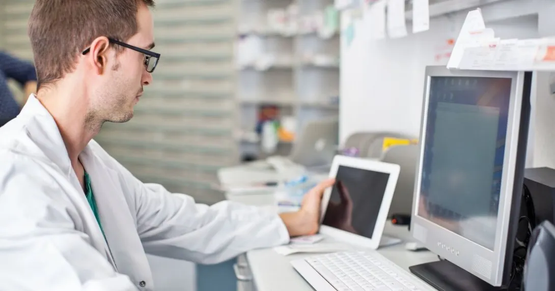 A clinician using a digital tablet and desktop computer