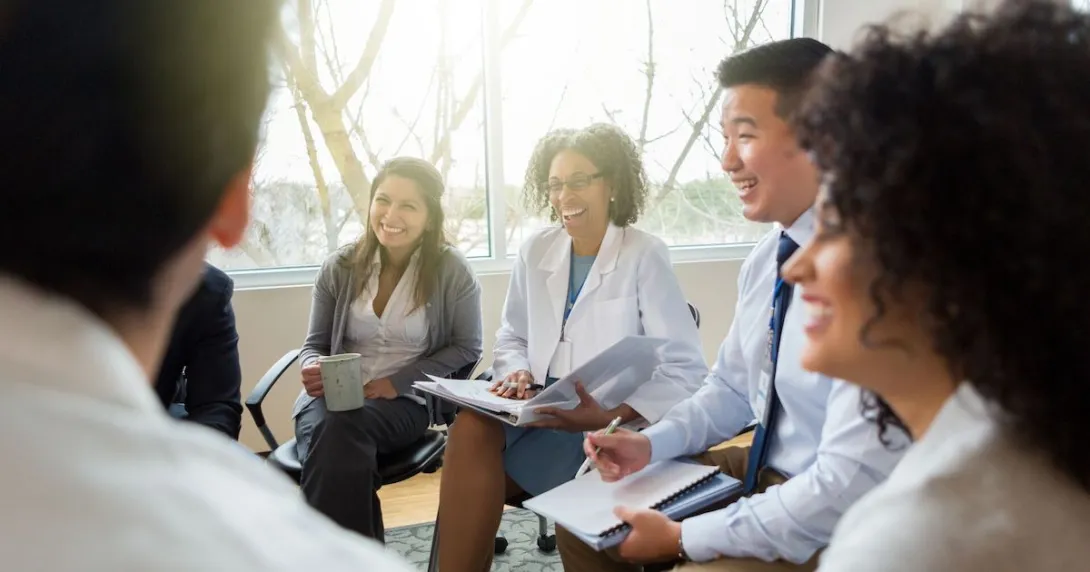 Laughing hospital administrators sitting down in a circle for a discussion