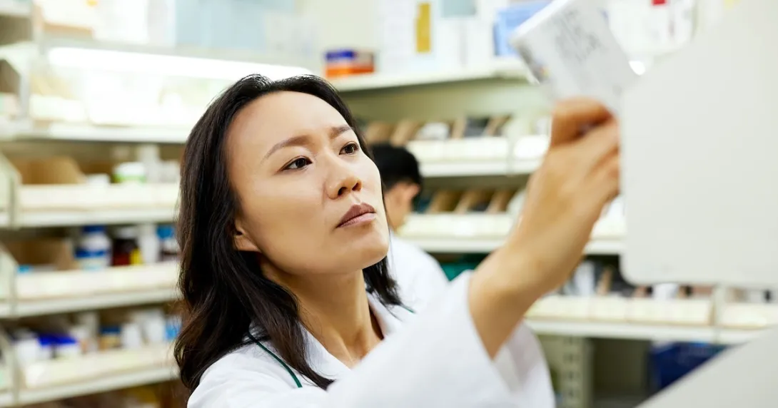 A pharmacist arranging a medicine rack at a pharmacy