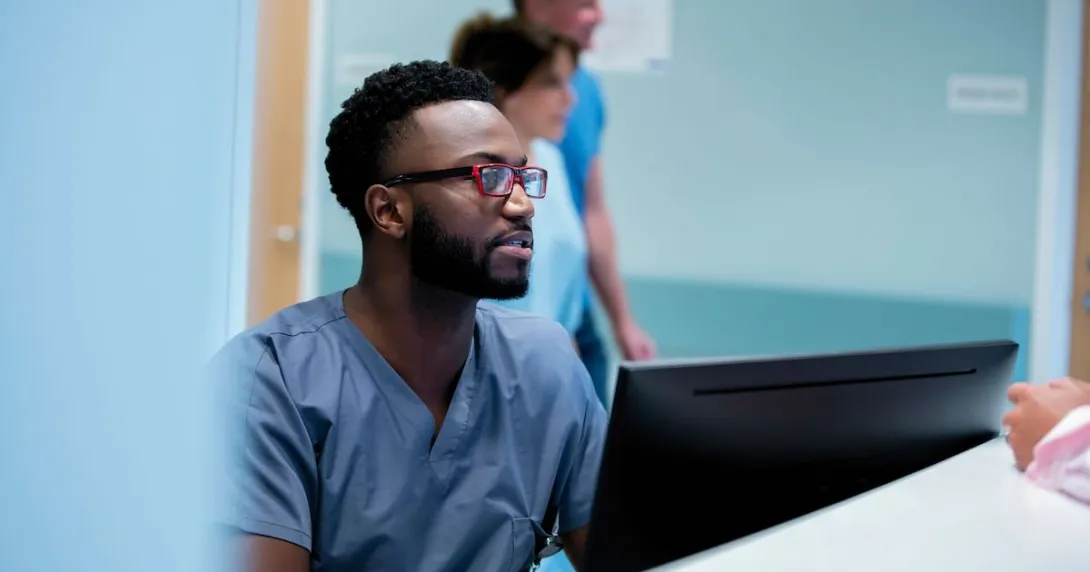 A nurse registering a patient on a desktop computer