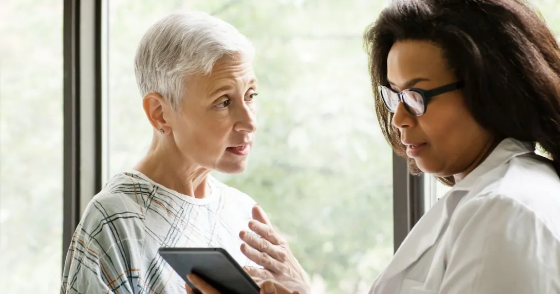 A doctor explaining a senior patient's test results using a digital tablet