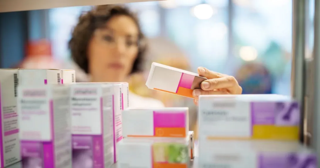 A pharmacist checking medicines on a rack
