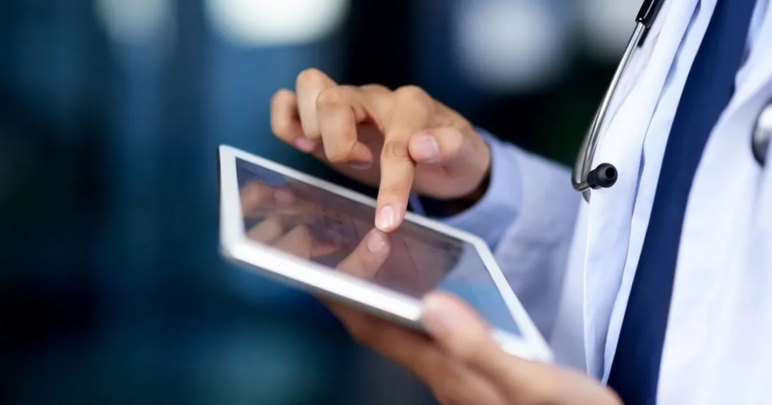Close-up of a clinician's hands reviewing patient data on tablet