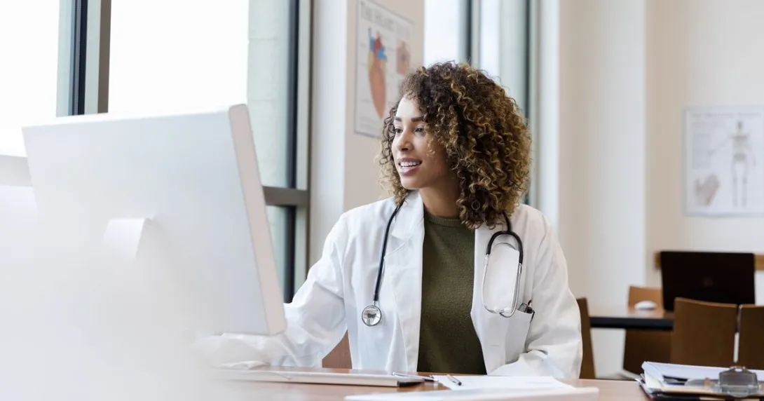 A doctor reviewing a patient's medical record on a desktop computer