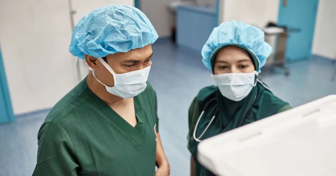 Two surgeons checking on an operation's progress through a digital monitor