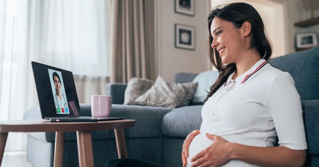 A pregnant person consulting with their doctor via video chat on a laptop