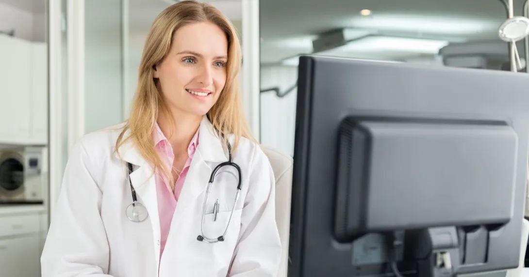 Doctor looks at a desktop computer screen in a medical office