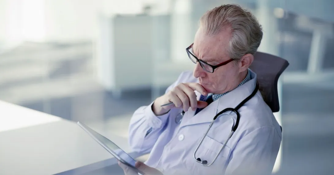 A doctor reviewing a patient's record on a digital tablet.