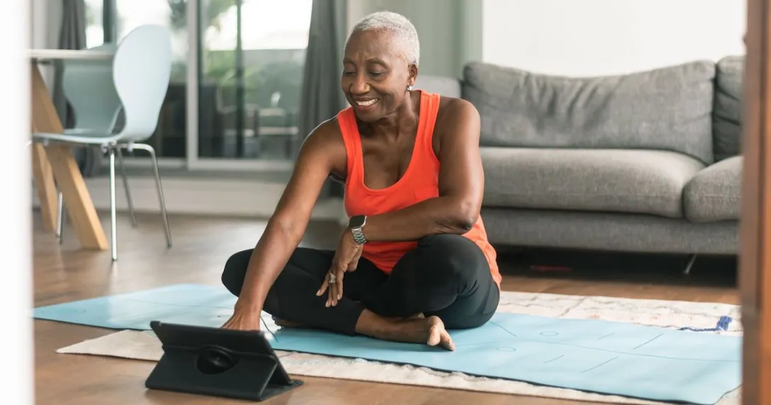 Person sits on a yoga mat with a tablet